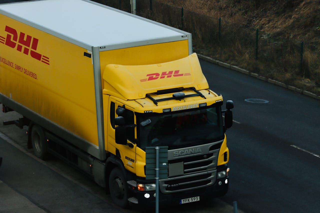 Yellow DHL delivery truck driving along a city road showcasing logistics in action.